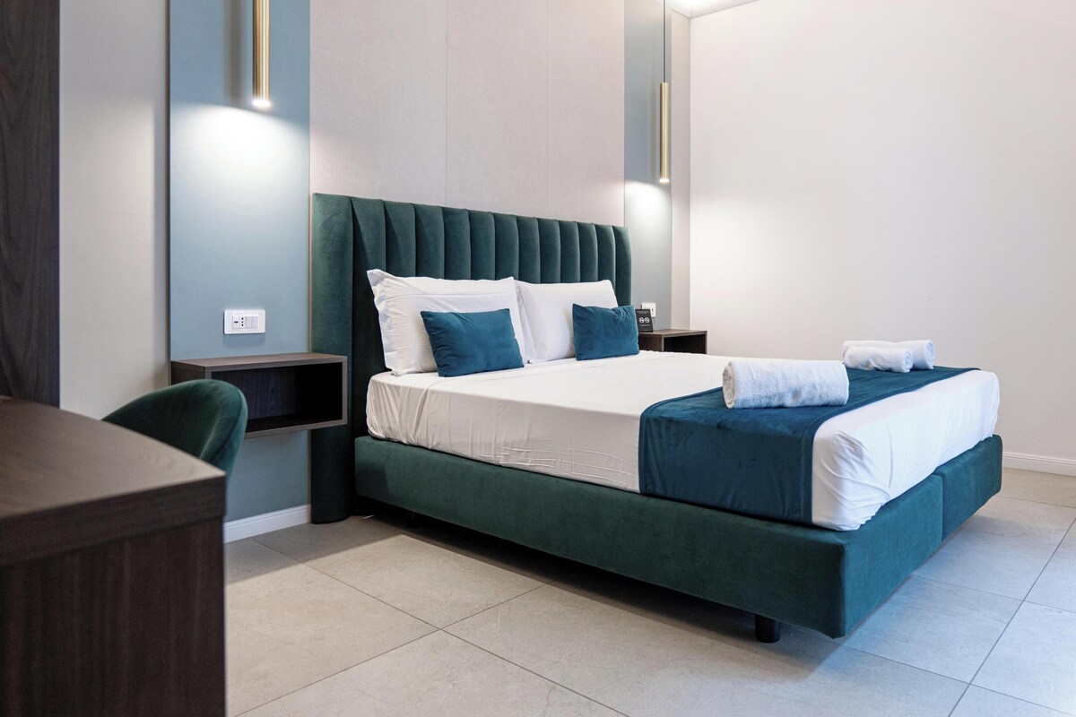 A modern hotel room with a large bed, a desk, and a chair.