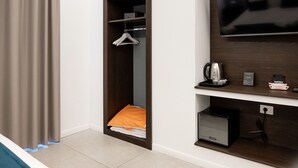 A hotel room with a walk-in closet, a flat-screen TV, a kettle, and a small safe. - Museo Suite (Naples)
