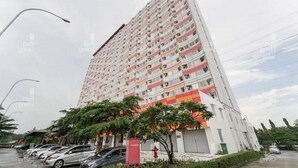 A tall, multi-story building with a white facade and red accents. - OYO 93906 Kingdom Property (Cikarang)