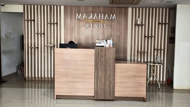 A reception desk with a wooden finish and a sign above it that reads "MANHARAM HOTEL". - OYO 93906 Kingdom Property (Cikarang)