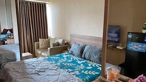 A hotel room with two beds, a sofa, a TV, and a minibar. - OYO 93906 Kingdom Property (Cikarang)