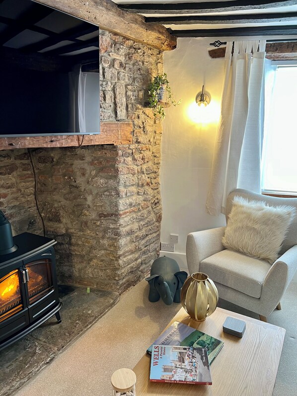 A cozy living room with a stone fireplace, a comfortable sofa, and a coffee table with books and a lamp. - Rennovated 2 bed dog friendly cosy cottage in central Wells (Wells)