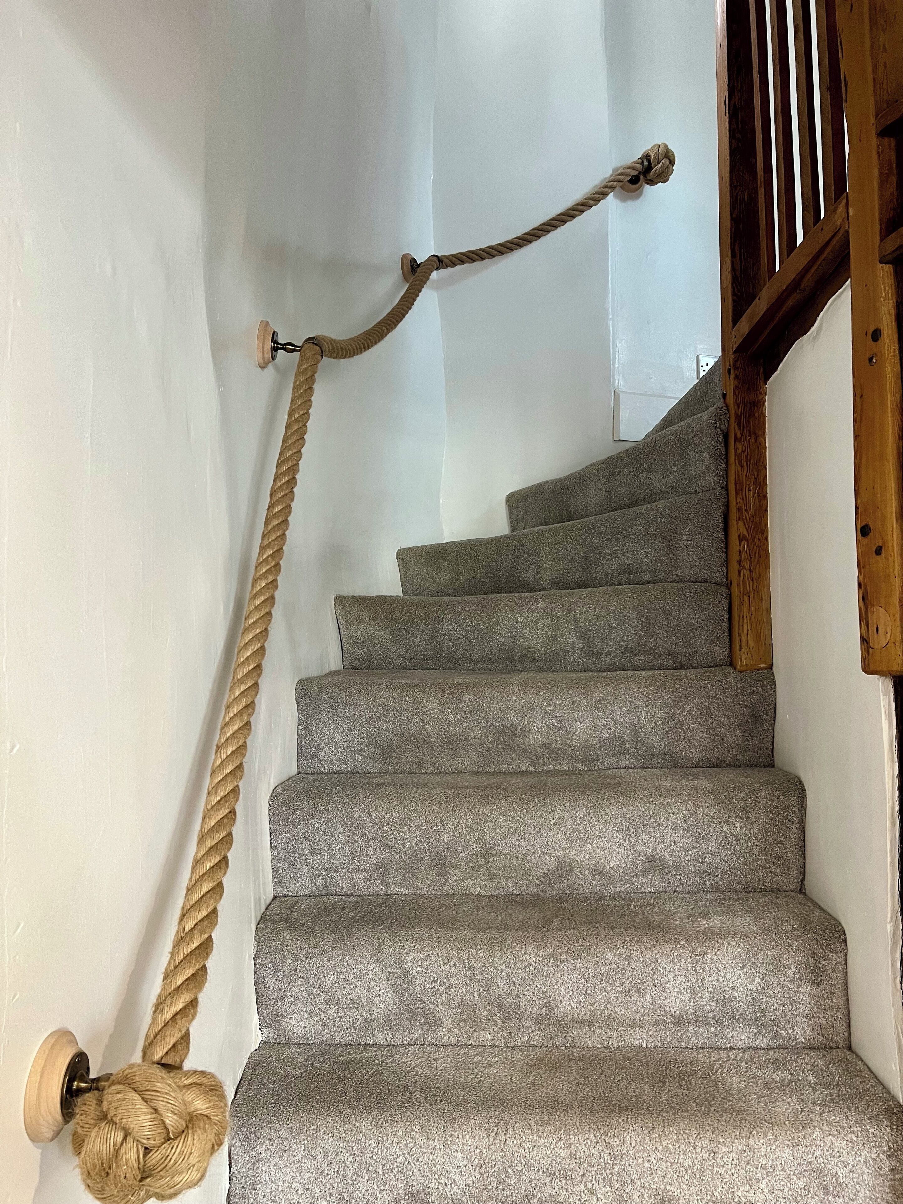 A staircase with a rope handrail and a wooden banister.