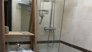 Ein Badezimmer mit einer Duschkabine, einem Waschbecken mit Spiegel darüber und einem Handtuchhalter.