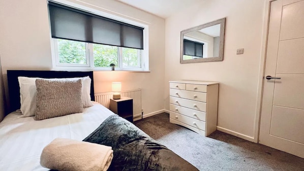 A bedroom with a bed, bedside lamp, dresser, and a door. - Stylish Townhouse With Free Parking in Liverpool (Liverpool)