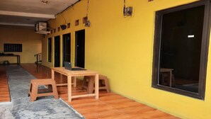 Ein Zimmer mit gelber Wand, einem großen Fenster und einem Holztisch mit zwei Hocker.