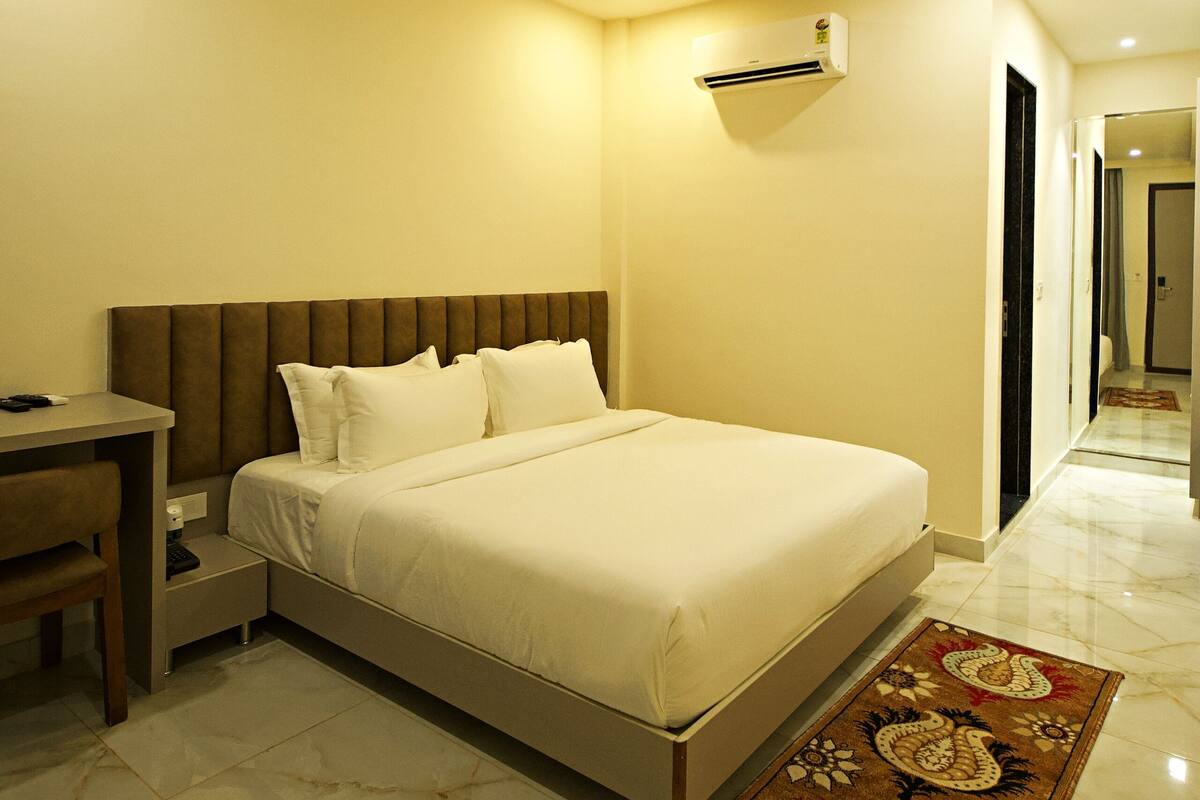 A hotel room with a bed, bedside table, and a desk.