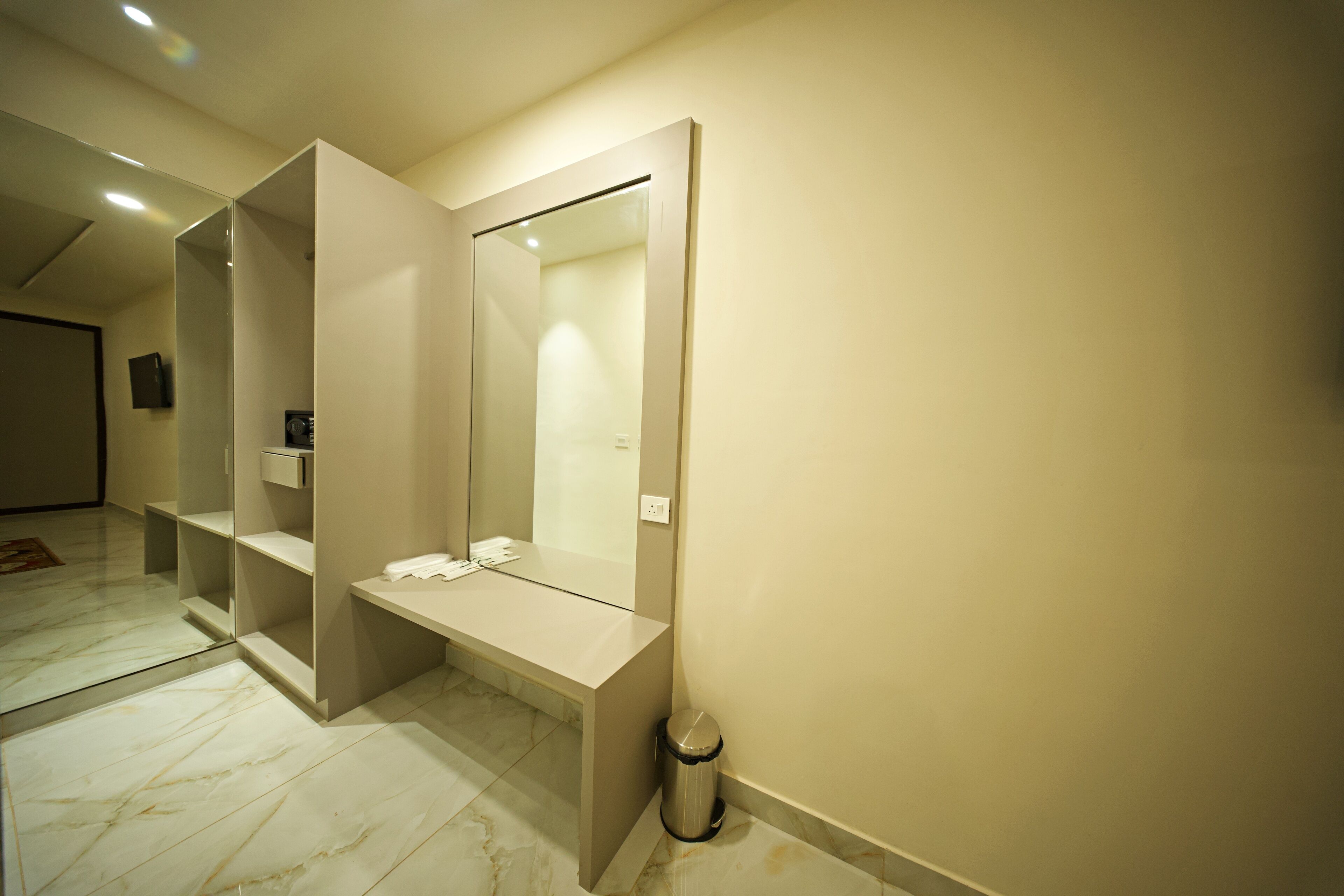 A modern bathroom with a large mirror, a vanity with a sink, and a trash can.
