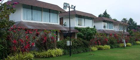 A row of modern two-story houses with large windows, surrounded by well-maintained gardens and a clear sky.