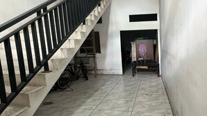 A staircase with a black railing leading to a landing. A bicycle is parked against the wall, and a chair is visible in the background.