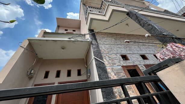 A multi-story building with a modern architectural design, featuring a prominent balcony and a series of windows.