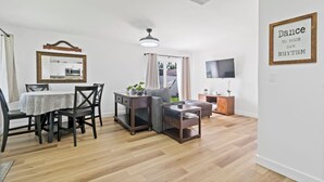 A modern living room with a dining area, a TV, and a motivational quote on the wall. - Cozy 2BD Near Ft. Myers Beach (Ft. Myers)