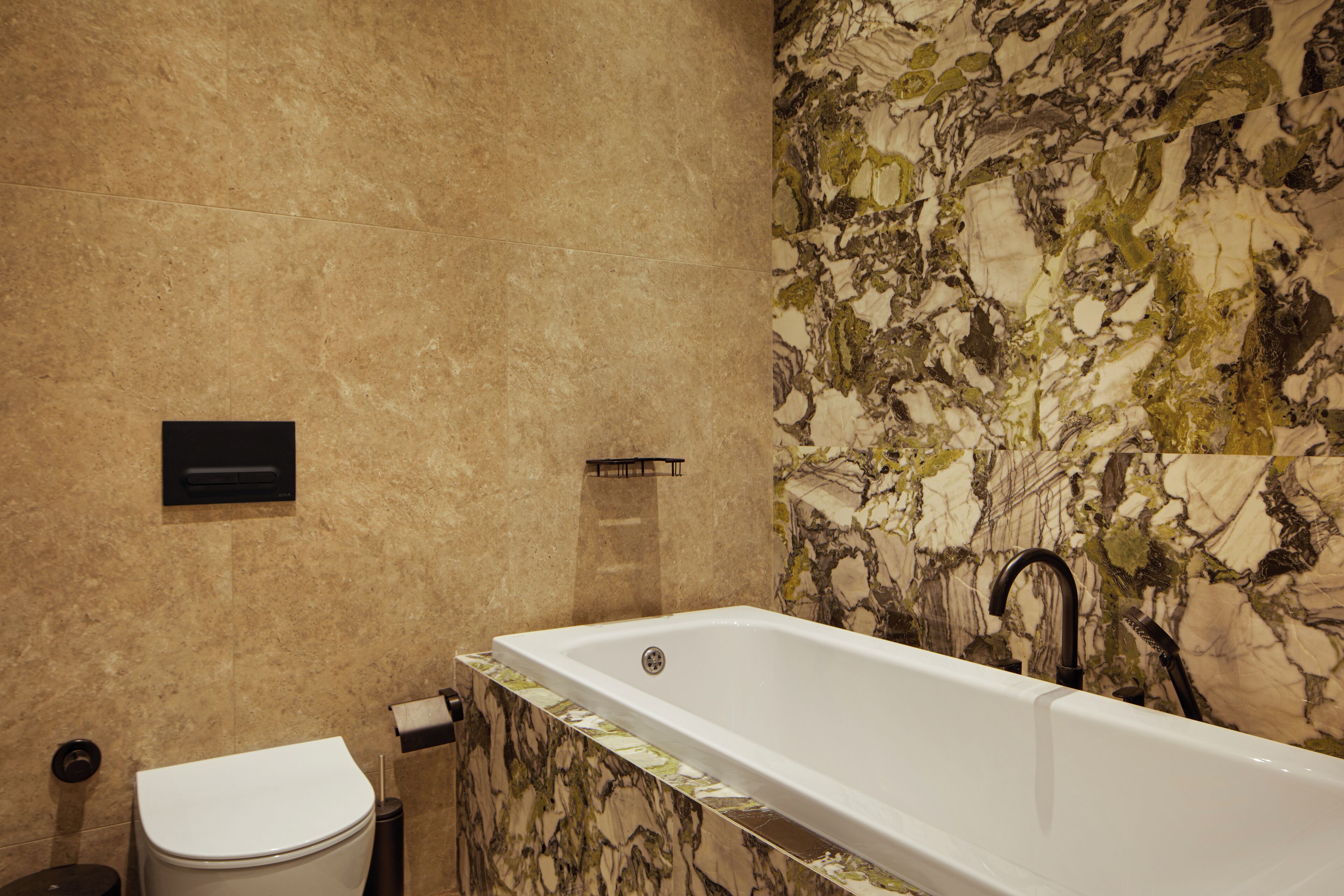 A bathroom with a marble wall, a bathtub, a toilet, and a towel rack.