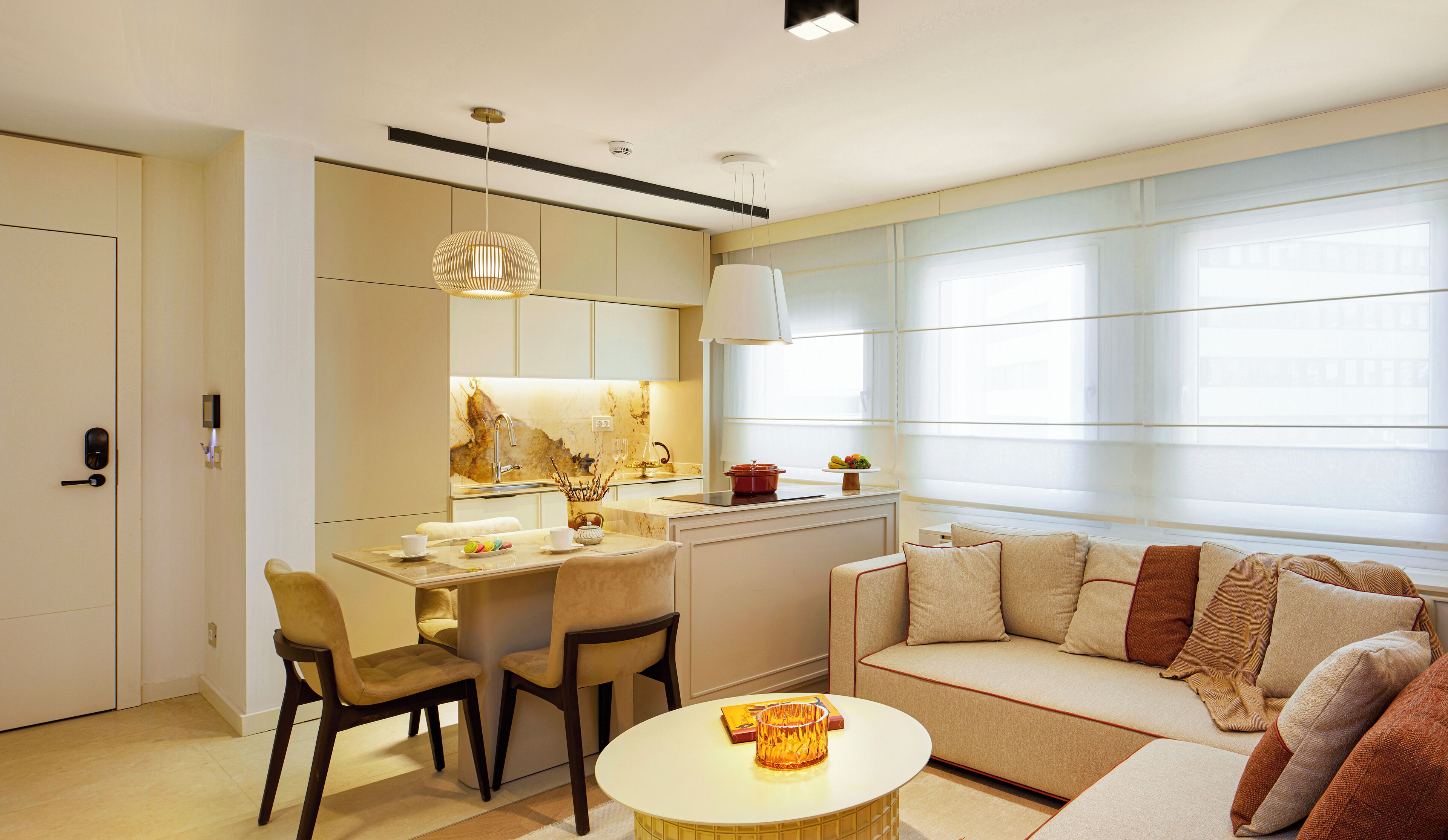 A modern living room with a sofa, a dining area with chairs, a kitchen with a sink, and a large window.