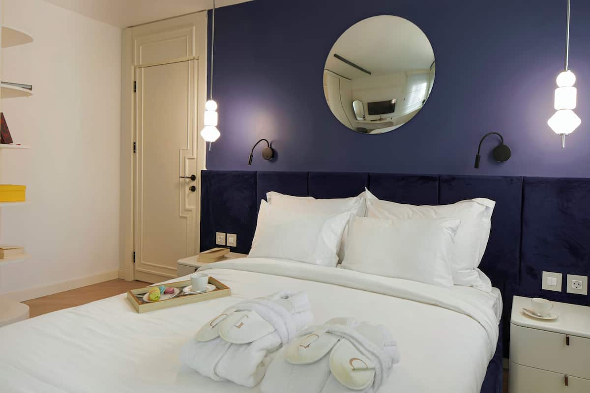 A neatly made bed with white linens, a tray of breakfast items, and towels on the bed.