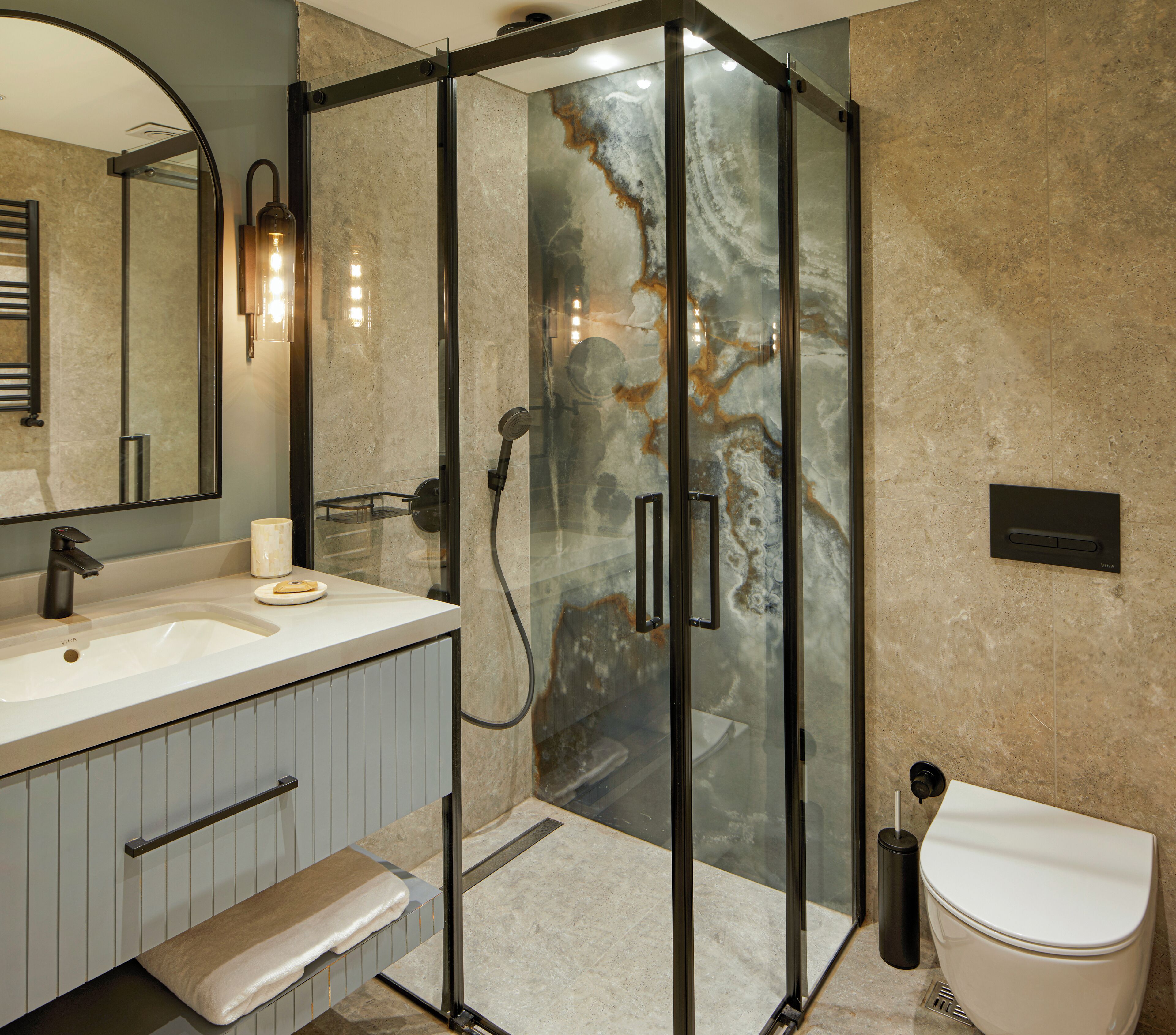 A modern bathroom with a glass-enclosed shower, a sink with a vanity, and a toilet.
