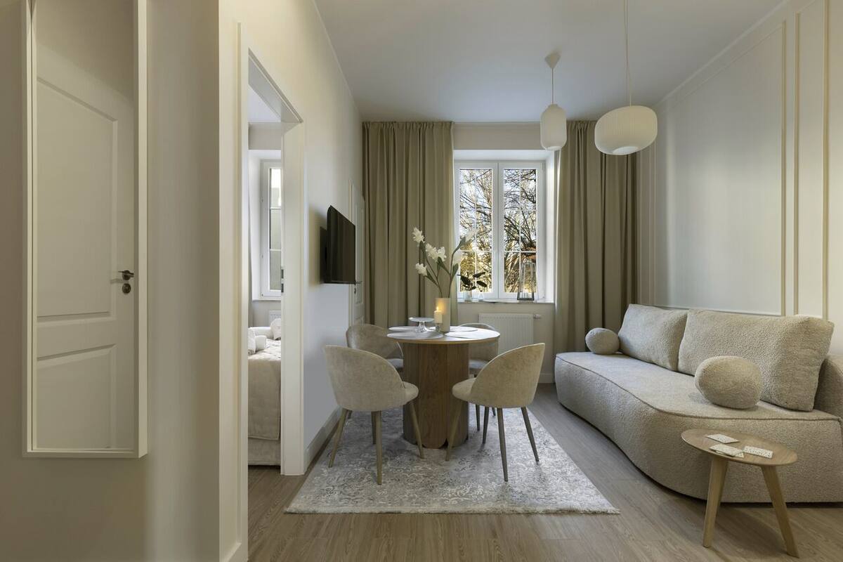 A modern living room with a sofa, chairs, a round table, and a TV.