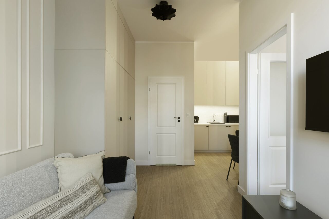 Una sala de estar moderna y minimalista con un sofá, una mesa de centro y un televisor montado en la pared.