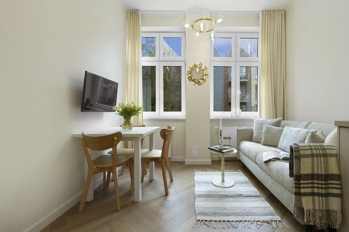 A living room with a sofa, a coffee table, and a TV mounted on the wall.