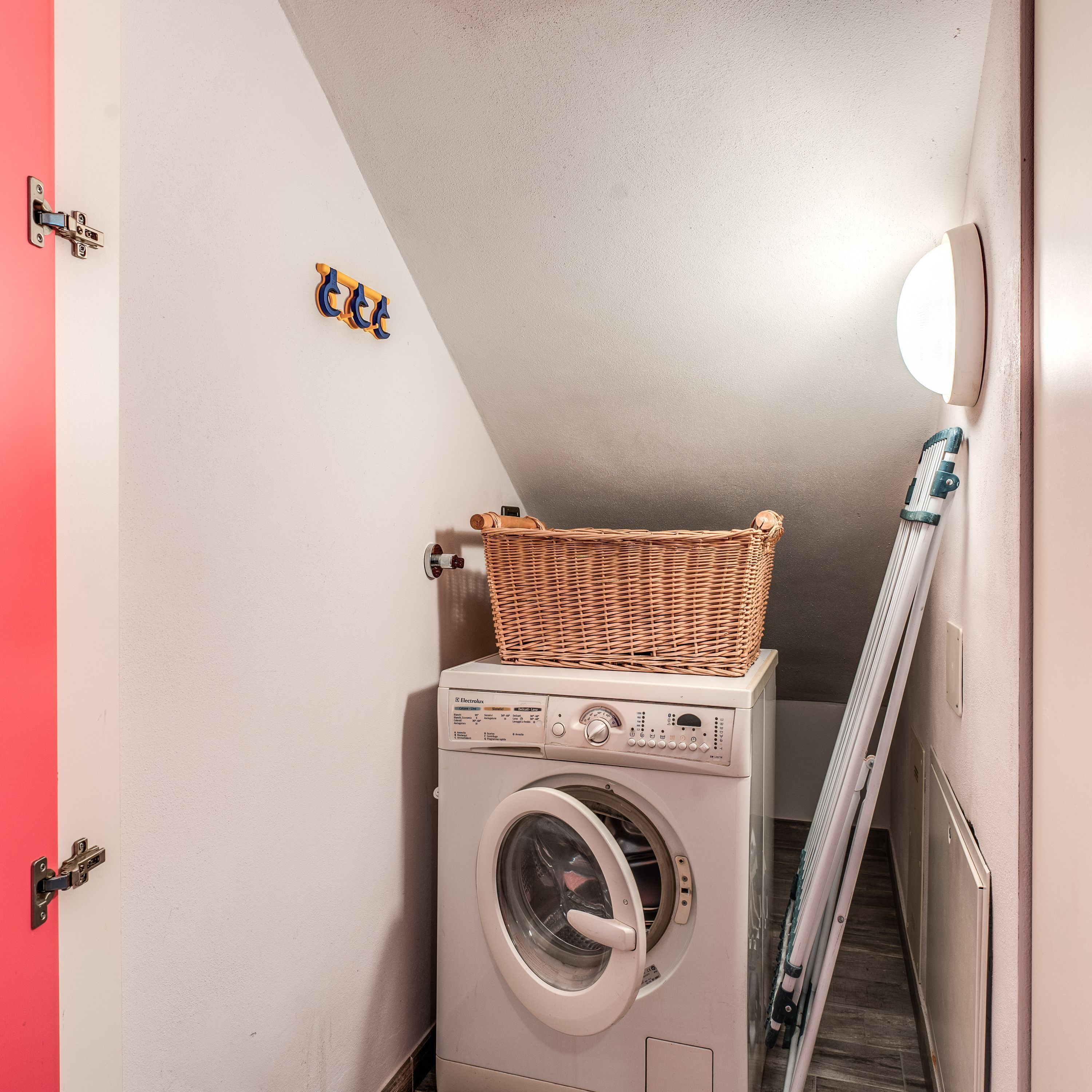 Une buanderie avec un lave-linge et un panier en osier posé sur le dessus.