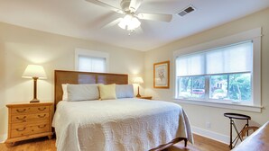 Ein Schlafzimmer mit einem großen Bett, zwei Nachttischen mit Lampen, einem Deckenventilator und einem Fenster mit Jalousien.