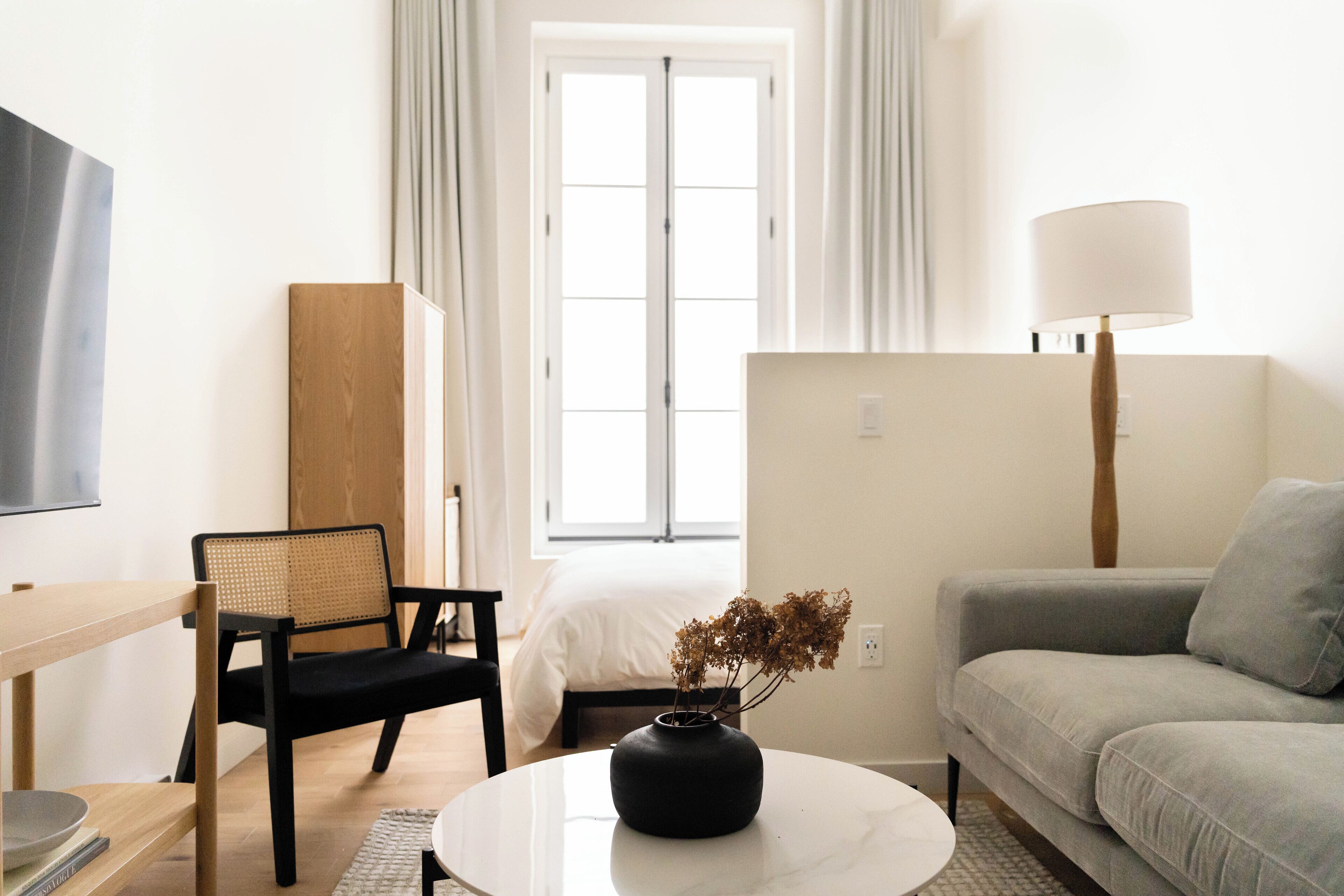 Una camera moderna e luminosa con un letto, un divano, un tavolo da pranzo e una lampada.