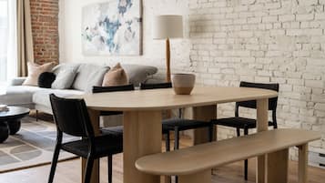 Un coin repas comprenant une table ronde, quatre chaises, un banc et une lampe.