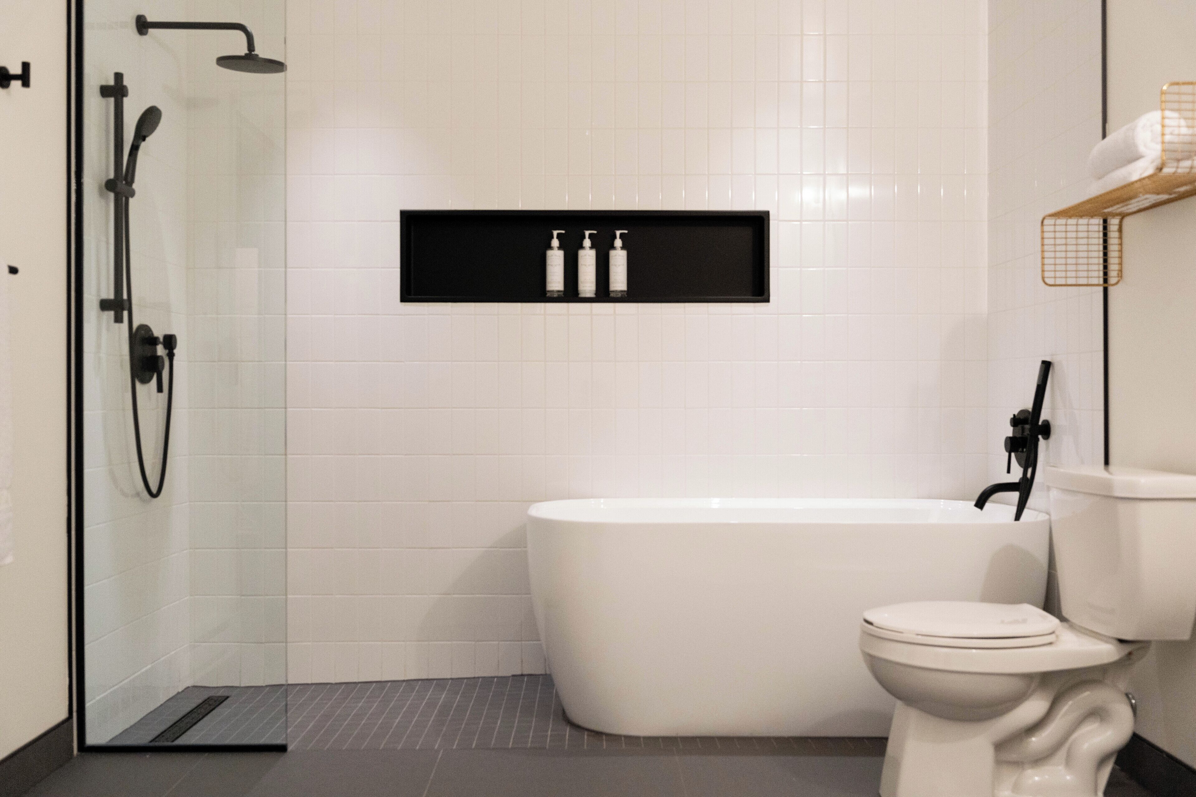 Un baño moderno con ducha de vidrio, una bañera blanca y un inodoro.