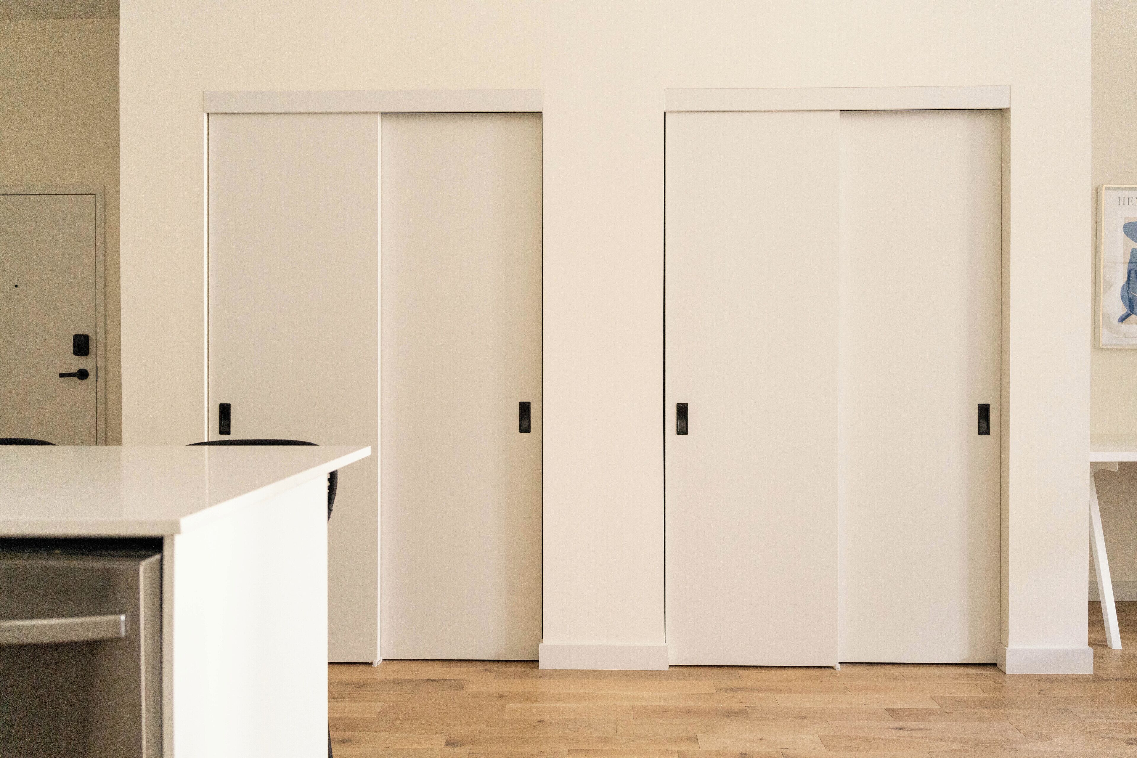 A room with a wooden floor, white walls, and a white door with a black handle.