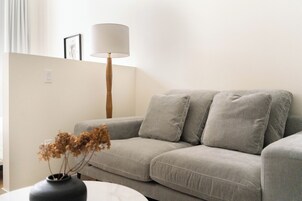 A modern living room with a grey sofa, a floor lamp, and a vase with dried flowers.