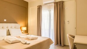 Una habitación de hotel con una cama grande, una mesita de noche con lámpara, una silla y un escritorio.