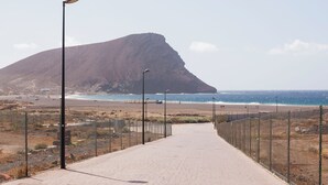 A paved pathway leading to a beach with a mountain in the background. - Ocean Paradise 2 la Tejita (Intero appartamento, due camere e un bagno) (Granadilla de Abona)