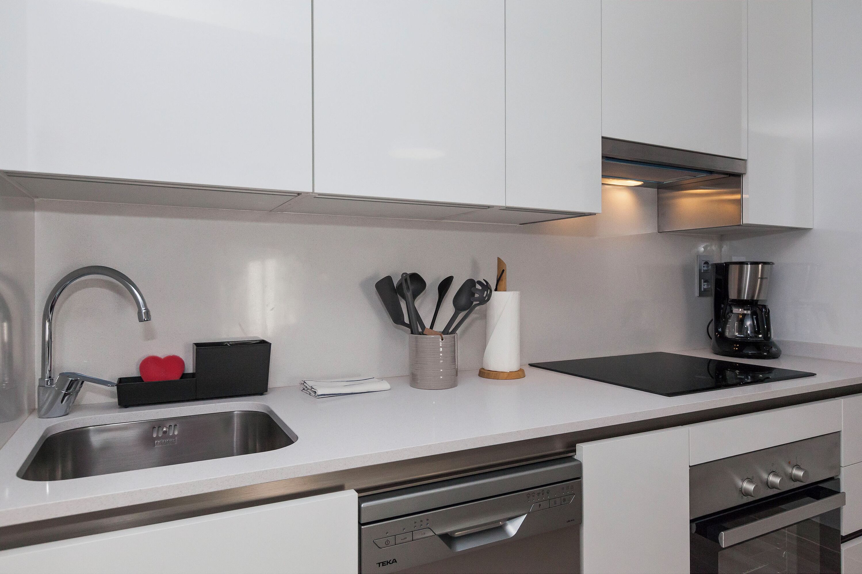 A modern kitchen with a stainless steel sink, a coffee maker, and a dishwasher.