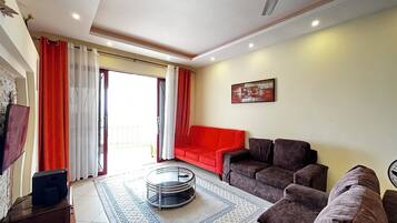 A living room with a red sofa, a brown sofa, a glass coffee table, and a ceiling fan.