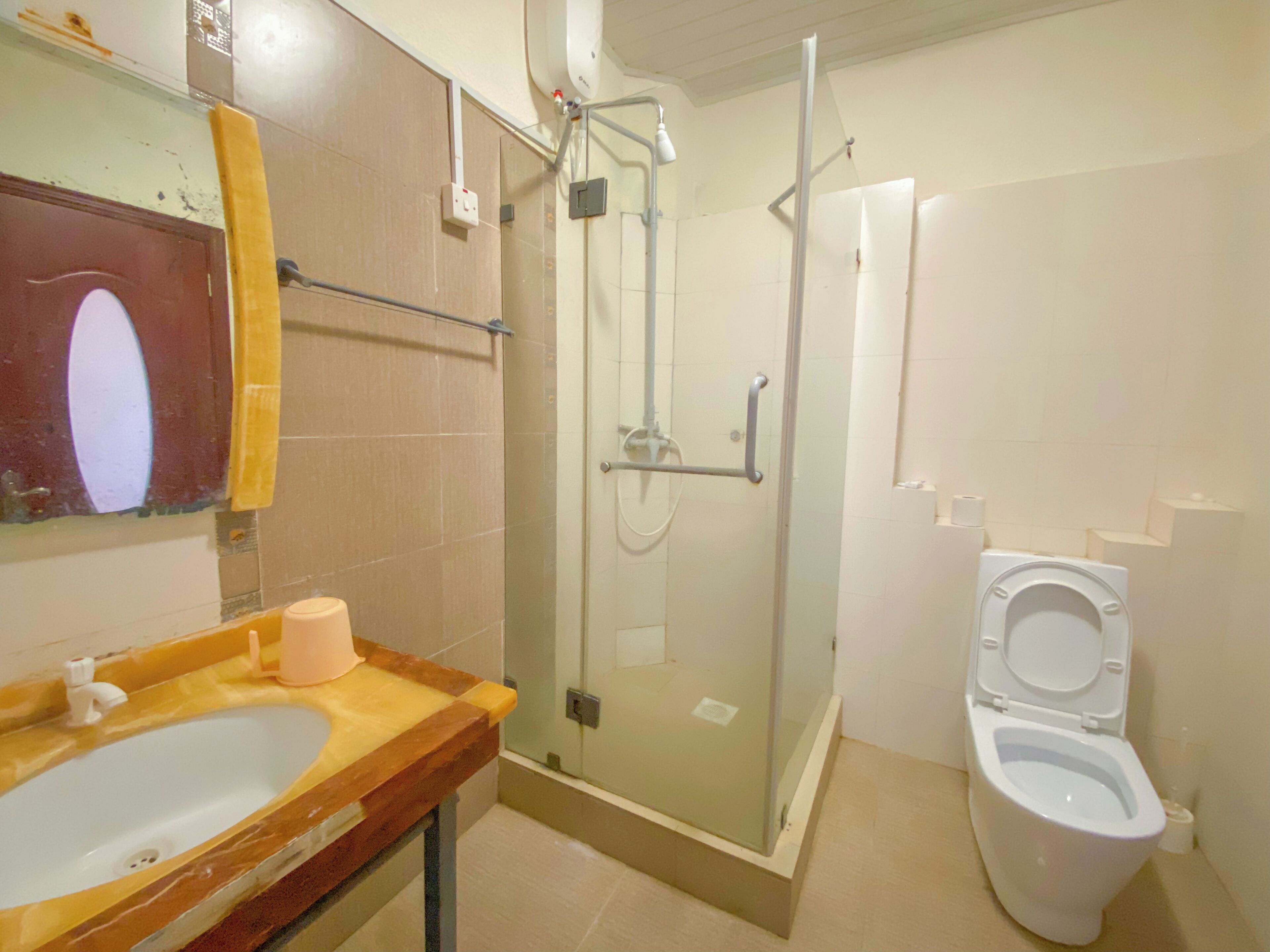 Une salle de bain avec une douche à parois de verre, un lavabo avec un miroir et des toilettes.