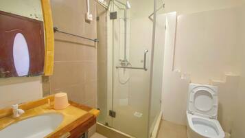 Une salle de bain avec une douche à parois de verre, un lavabo avec un miroir et des toilettes.