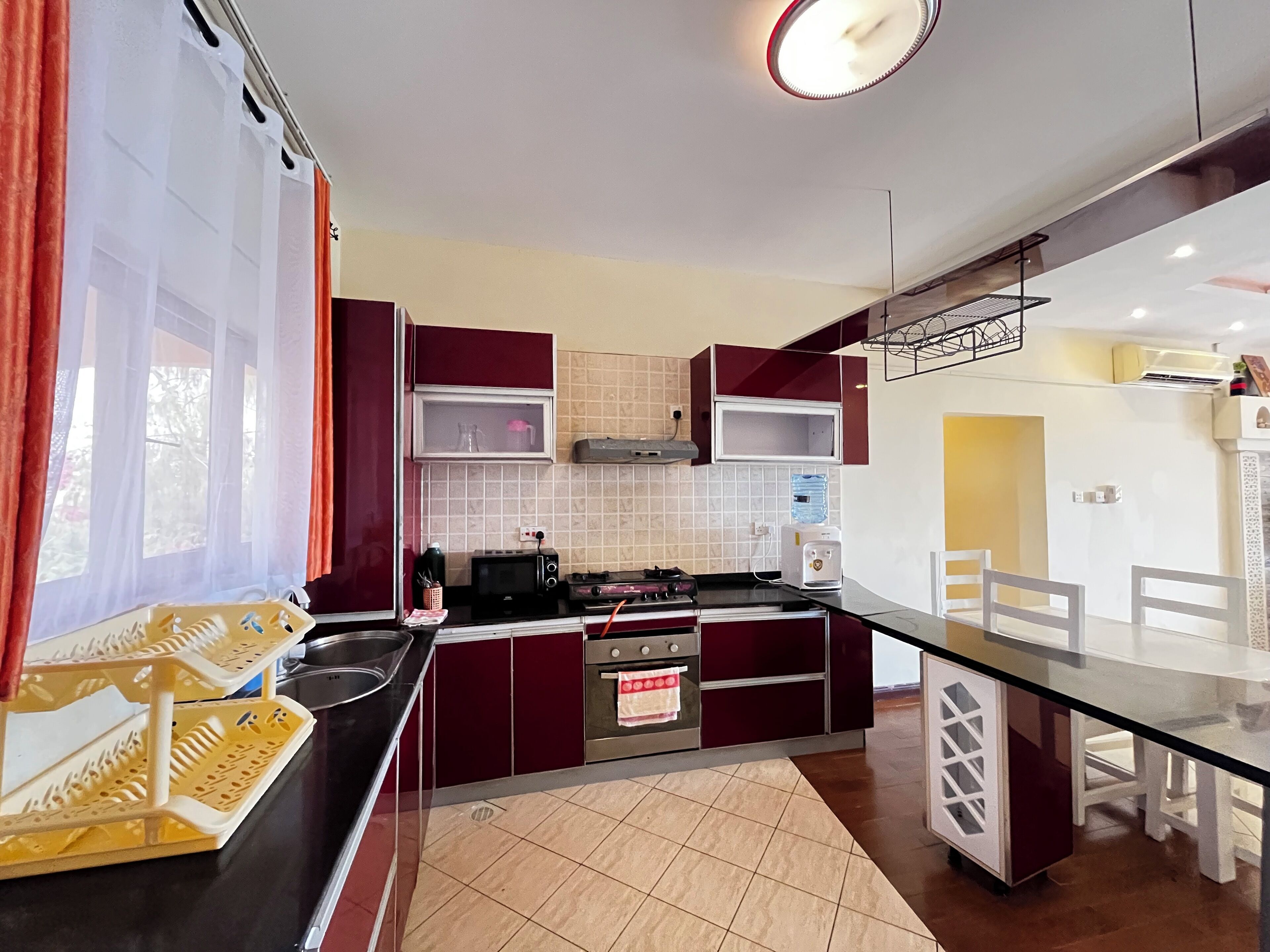 A modern kitchen with a black countertop, red and white cabinets, a built-in oven, and a water dispenser.