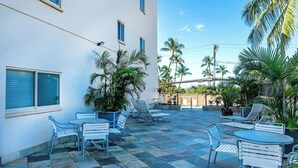 A courtyard with a pool, outdoor seating, and palm trees. - Summer Deal Oceanfront Kihei Penthouse with 32 Ft Lanai and Views (Kihei)