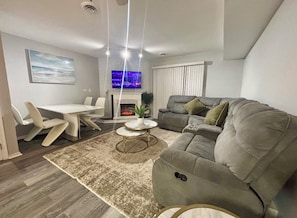 A modern living room with a sofa, a dining table, and a fireplace.