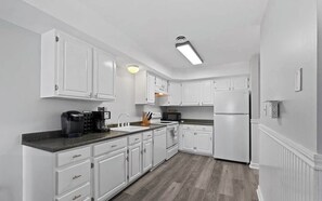 A modern kitchen with white cabinets, a black countertop, and a built-in microwave.