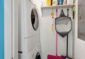 Un'area lavanderia con lavatrice, stendibiancheria e prodotti per la pulizia.
