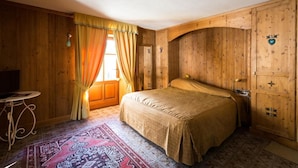 A wooden room with a bed, a small table, and a window with curtains. - Hotel Lyshaus di Gressoney Saint Jean (Gressoney-Saint-Jean)