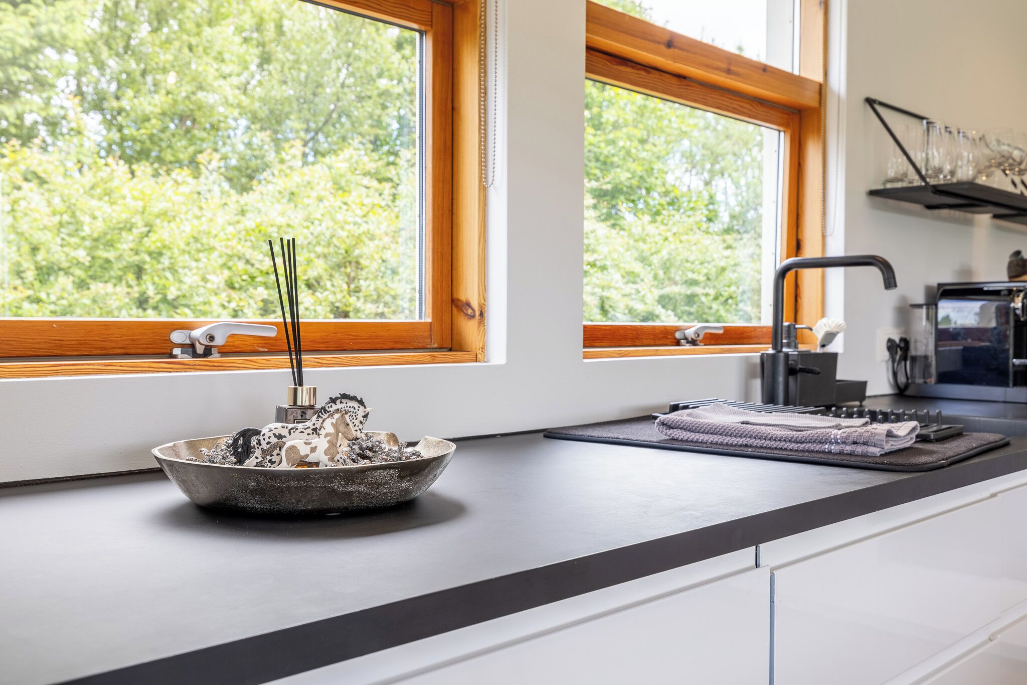 A kitchen with a bowl of spices, a coffee machine, and a window with a view of trees.