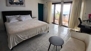 A bedroom with a bed, a ceiling fan, a chair, and a view of the outdoors through a sliding door. - Beautiful spacious Studio with spectacular view (cole bay)