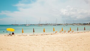A beach with rows of sun loungers and umbrellas, a clear sky, and sailboats in the background. - Beautiful spacious Studio with spectacular view (cole bay)