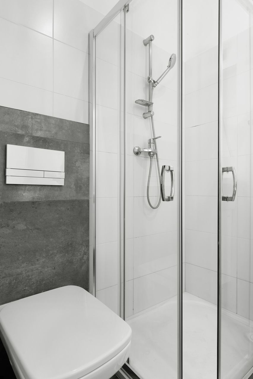 A modern bathroom with a glass-enclosed shower, a white toilet, and a towel rack.