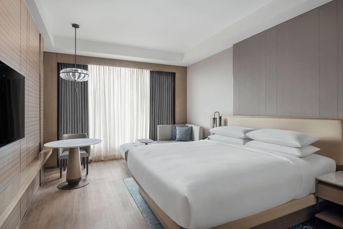 Een moderne hotelkamer met een groot bed, een televisie, een eettafel en een zithoek.