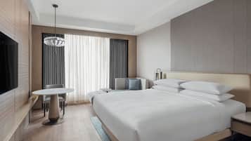 Una habitación de hotel moderna con una cama grande, televisión, una mesa de comedor y un espacio para sentarse.