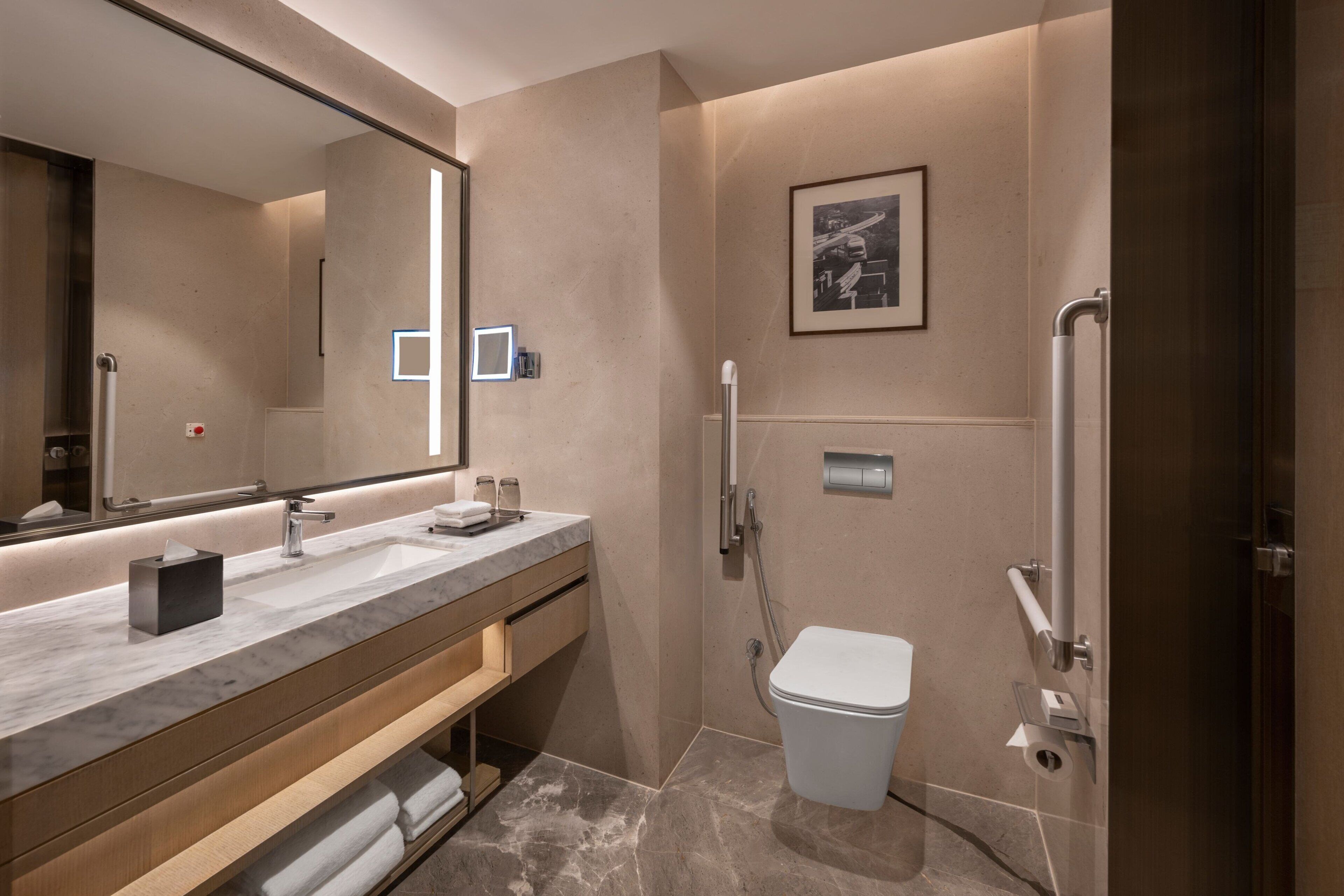 A modern bathroom with a large mirror, dual sinks, a toilet, and a shower.