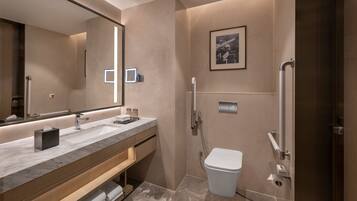 Une salle de bain moderne dotée d’un grand miroir, de deux vasques, de toilettes et d’une douche.